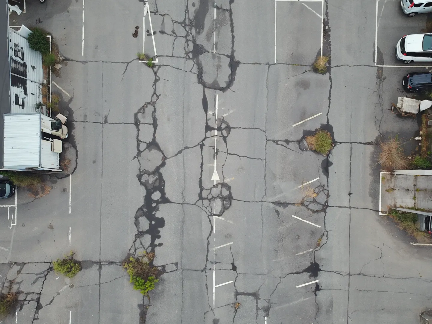 Exemple de stationnement commercial dégradé avant les travaux (visuel d’illustration)